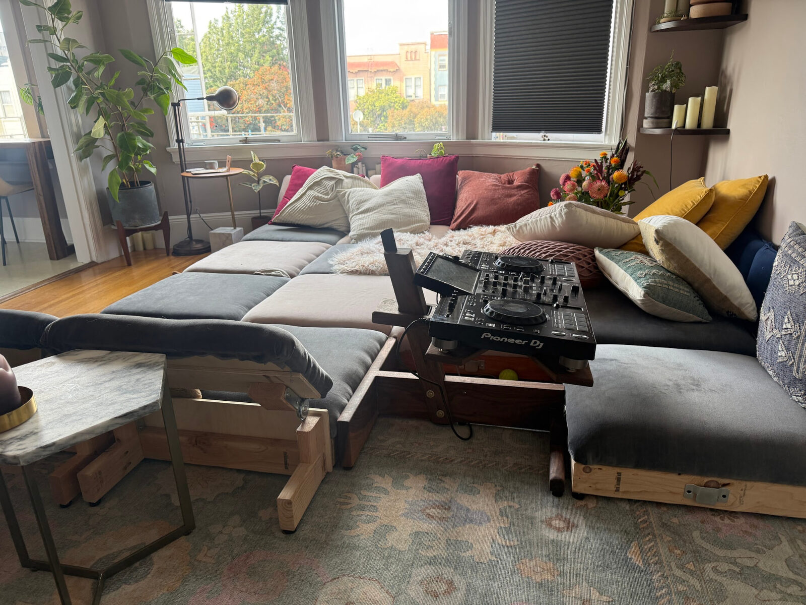 Modular grey sectional with warm cushions around a bay window